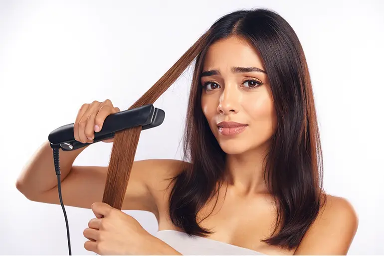 Mujer alisando el pelo con una plancha de pelo